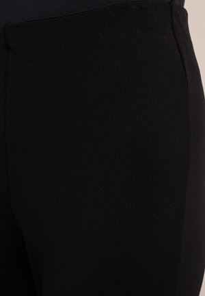 Leggings noirs à côtes en matériau élastique, avec une texture lisse et un design ajusté. Pas de matériel ou de motifs visibles.