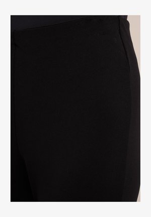 Zwarte geribbelde legging van elastisch materiaal, met een gladde textuur en een aansluitend ontwerp. Geen zichtbare hardware of patronen.