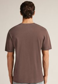 Hnědá bavlněná trička s krátkými rukávy a kulatým výstřihem. Má mírně texturovaný povrch a standardní střih.