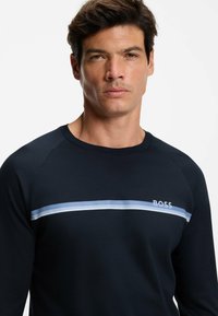 Maglia a maniche lunghe color blu marino in misto cotone con righe orizzontali azzurre e bianche; logo "BOSS" sul petto, scollo rotondo.