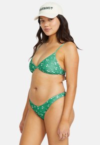 Grön blommig bikiniuppsättning med triangeltopp och tunna remmar. Tillverkad av lättviktsmaterial med en subtil ribbad textur.