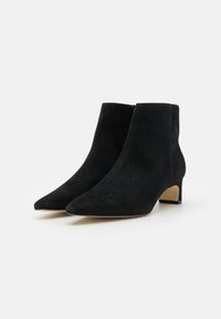 Botines de ante negro con punta afilada y tacón bajo y bloque. Textura suave y diseño minimalista. Cierre de cremallera en la parte trasera.