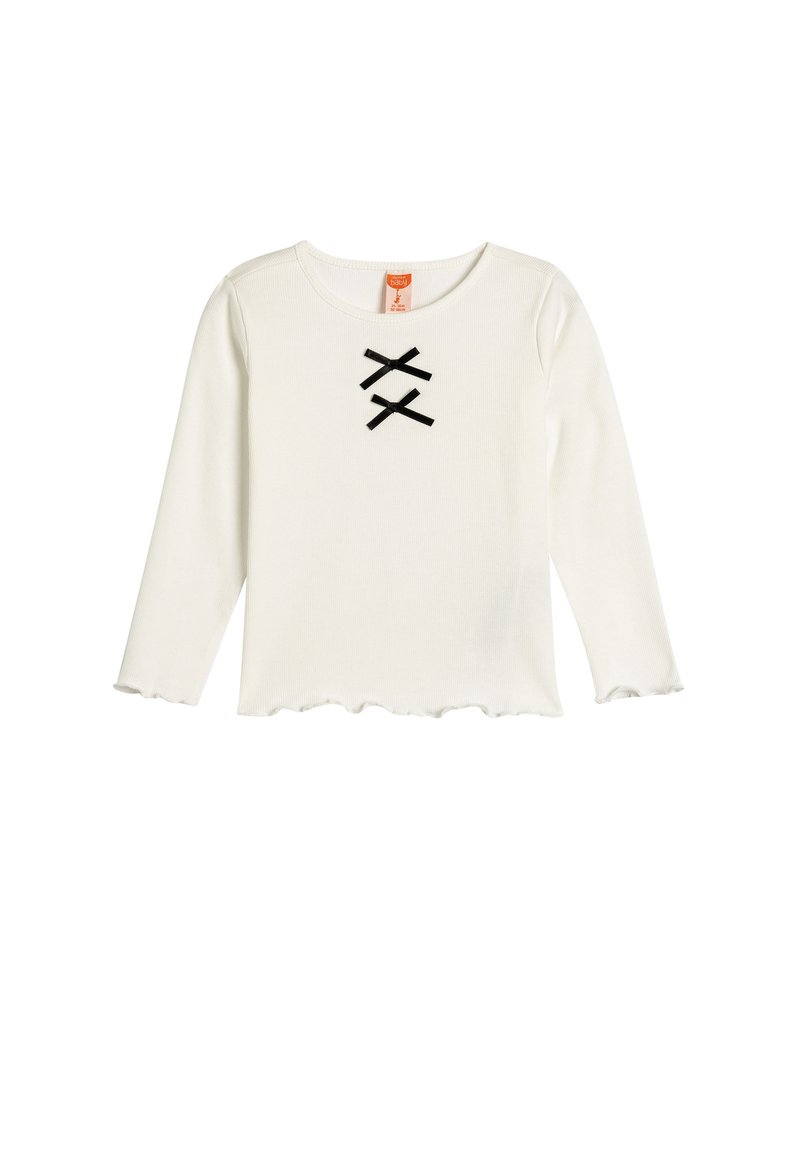 Haut blanc à manches longues avec un col rond et un ourlet festonné. Présente deux accents en ruban noir formant un motif en "X" sur le devant.