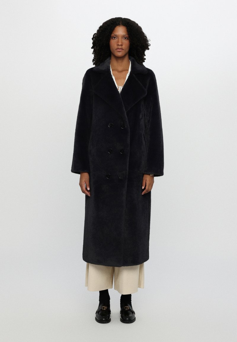 Long, dark navy coat made of soft, textured fabric. Features a double-breasted design with large black buttons and a wide collar.