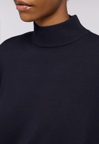 Maglione a dolcevita navy realizzato in tessuto a coste, con un colletto aderente e una texture liscia.