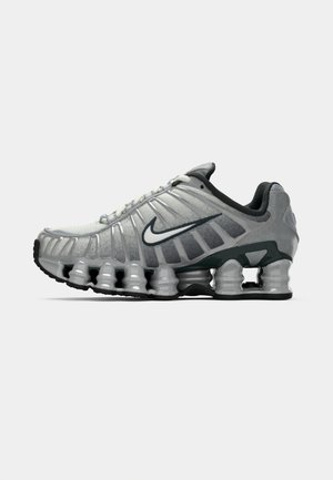 Grey and black Nike running shoe with visible spring-like cushioning under the sole and a white swoosh logo on the side.