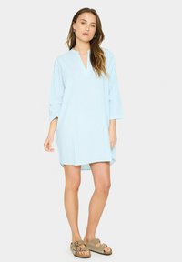 Blau-weiß gestreiftes Kleid mit Stehkragen und Dreiviertelärmeln. Leichter Stoff und lockere Passform. Oberschenkellang.