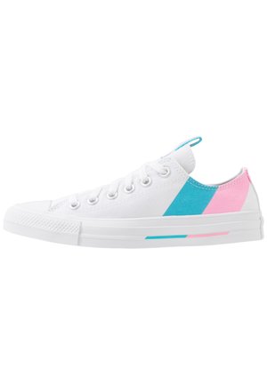 Baskets en toile blanches avec un design low-top, présentant des accents diagonaux bleus et roses sur les côtés et une semelle en caoutchouc texturée.