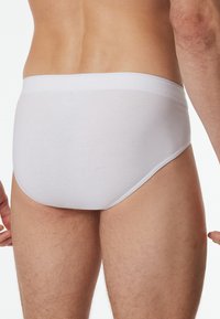 Weiße Baumwollunterwäsche in einfarbigem Design, mit glatter Textur, elastischem Bund und mittelhohem Schnitt. Einfaches Design ohne Muster.