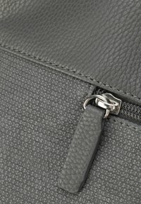 Borsa grigia con texture, dotata di una parte superiore in pelle liscia e corpo in tessuto pattern. Presenta una cerniera argentata e un tirazip texturizzato.