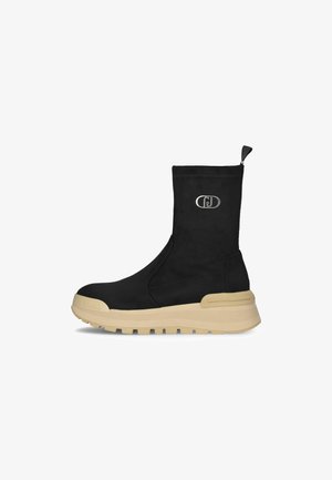 Stivaletti neri alla caviglia con una texture morbida simile alla pelle scamosciata, caratterizzati da una suola beige e un dettaglio del logo sul lato, progettati con una forma elegante e minimale.