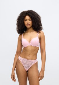 Σουτιέν από ροζ δαντέλα με μασκαρισμένα cups και λεπτές κυματιστές άκρες, σετ με τάνγκα από ταιριαστή δαντέλα με λουλουδάτα σχέδια και λεπτές πλευρές.