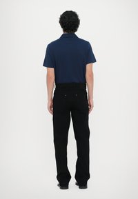 Navy polo shirt with short sleeves paired with black straight-leg jeans. Solid color, smooth fabric, and minimal hardware details.