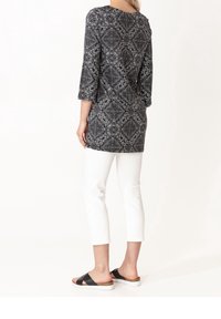 Svart och vit mönstrad tunika med trekvarts ärmar, ihop med vita cropped byxor och svarta sandaletter med remmar.