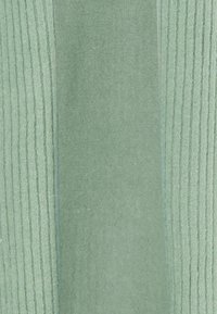 Tessuto verde chiaro con aree lisce e rigate, dalla consistenza morbida e colore uniforme. Nessun motivo o dettaglio visibile.