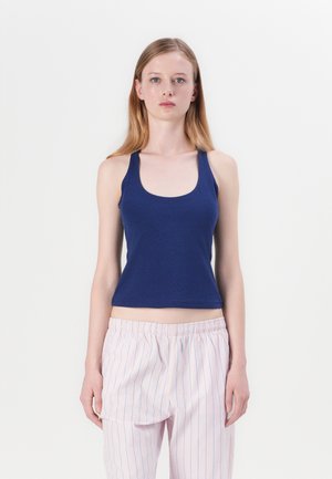 Débardeur bleu marine avec un col en U et des bretelles larges, fabriqué à partir d'un tissu lisse et extensible. Accompagné d'un pantalon de pyjama rayé rose clair.