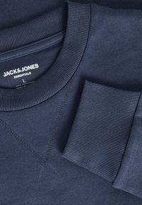 Mörkblå sweatshirt med ribbad halsringning och ficka. Har en jämn yta och sydda detaljer. Varumärkesetikett synlig inuti kragen.