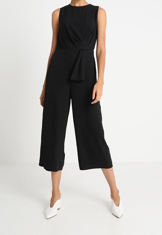 Czarny kombinezon bez rękawów z dopasowanym topem, wiązanym w pasie oraz szerokimi, skróconymi nogawkami. Gładki materiał o subtelnym połysku.