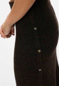 Robe en maille ribotée en tissu marron foncé, dotée d'une taille haute et d'une fermeture latérale avec quatre boutons ronds.