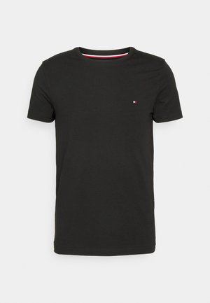 T-shirt noir en coton à manches courtes et col rond, arborant un petit logo rouge, blanc et bleu sur la poitrine.