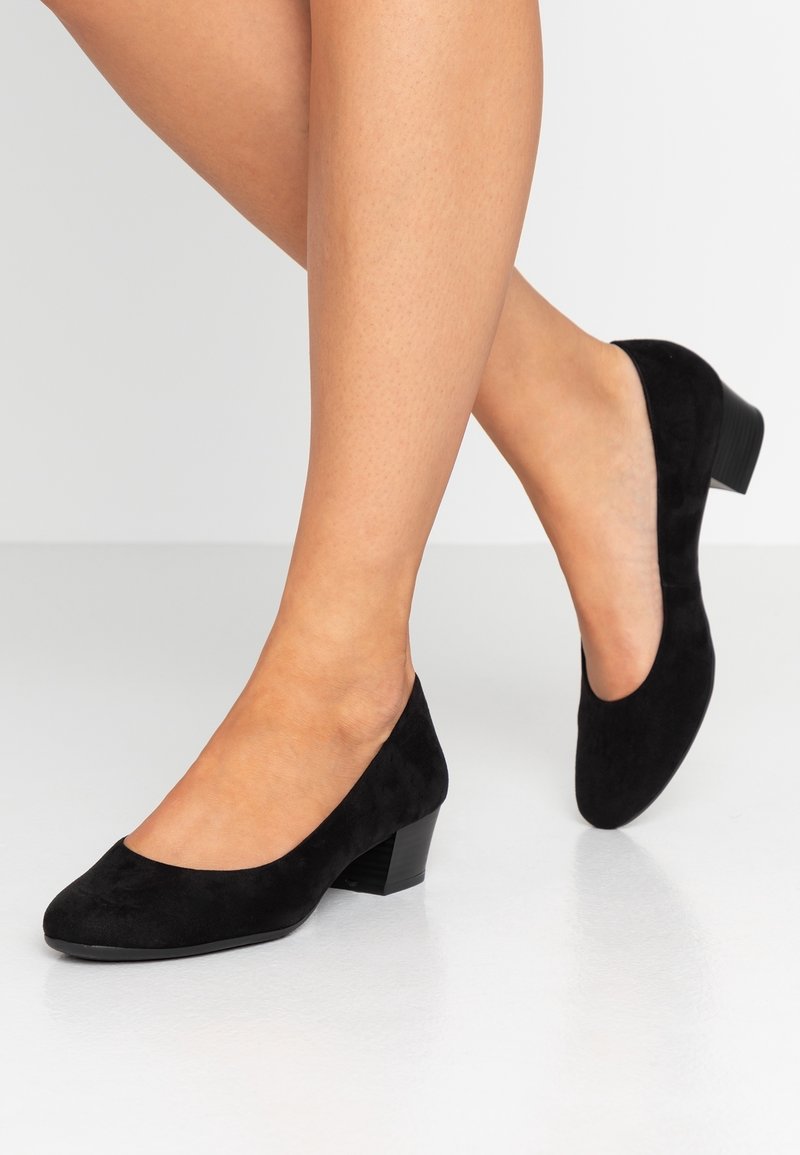 Escarpins en velours noir à talons bas avec un bout rond et une texture lisse, présentant un talon modeste et une silhouette classique.