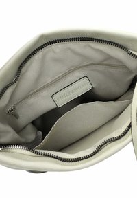 Interno di una borsa a tracolla grigia chiara con tessuto liscio, una tasca con zip e un'etichetta in pelle. I bordi sono cuciti con filo nero.