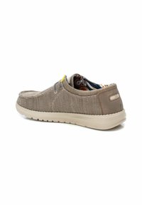 Zapatos slip-on de color marrón claro, hechos de un tejido texturizado con suela de goma contrastante. Acento colorido en el forro visible desde la abertura.