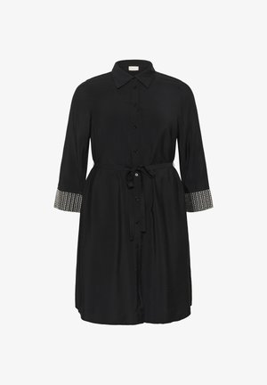 Robe chemise noire à longueur genou avec devant à boutons, ceinture à nouer à la taille, col pointu, manches 3/4 et poignets ornés de clous en argent.