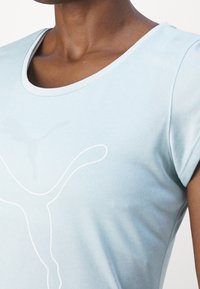 Vaaleansininen lyhythihainen t-paita, valmistettu pehmeästä kankaasta, jossa valkoinen logokuvio edessä ja pyöreä pääntie.