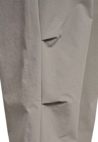 Jasnoszara tkanina o fakturowanym wykończeniu, z subtelnym zagięciem i dwoma wszytymi kieszeniami. Minimalistyczny design podkreśla czyste linie.