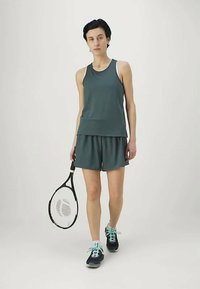Sporty tank top and shorts set in dark teal, made from lightweight fabric; paired with black shoes featuring teal accents and a tennis racket.