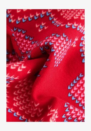 Punane kangas, millel on geomeetriline muster siniste, roosade ja valgete aktsentidega. Tekstuur on pehme ja veidi veniv.