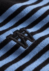 Tissu rayé noir et bleu clair avec une finition texturée. Présente un logo noir brodé à l'avant.