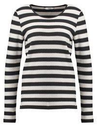Striped sweater with long sleeves, featuring alternating black and white colors. Knit texture, rounded neckline, and a relaxed fit.