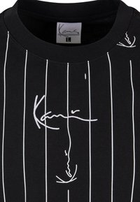 Black short-sleeve T-shirt featuring white vertical stripes and embroidered signature detail. Crew neckline with soft, smooth fabric texture.