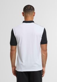 Pikétröja för herr med svart krage och ärmar, vit kropp, korta ärmar, mjuk textur och slim fit-design.