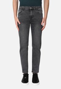 Jeans in denim grigio slim-fit con cinque tasche, chiusura a bottone, passanti per cintura e una leggera texture di lavaggio. Abbinati a sneaker nere.
