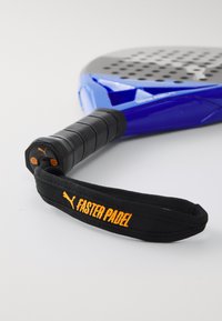 Racchetta da padel blu con impugnatura nera texture, dotata di un cinturino arancione "Faster Padel" e una testa perforata per prestazioni migliorate.
