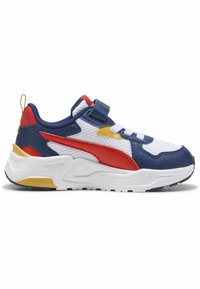 Baskets de sport bleu, rouge et jaune avec une sangle velcro, présentant une surface texturée et une semelle blanche. Vue de profil.