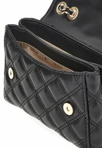 Pochette en cuir noir matelassé avec fermetures magnétiques dorées, chaîne en bandoulière et doublure intérieure beige estampillée "GUESS".