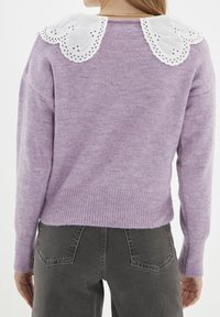 Maglione lilla con finitura texturizzata, caratterizzato da un colletto in pizzo bianco con bordi scalloppati. Orlo a costine e maniche lunghe.
