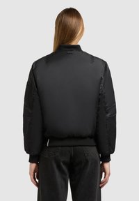 Giubbotto bomber imbottito nero con colletto e polsini a costine. Tessuto liscio, vita elasticizzata e tasche laterali. Design semplice, senza loghi visibili.