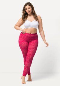 Spitzenleggings in leuchtendem Pink mit eng anliegendem Schnitt, versehen mit komplizierten Blumenmustern und einem glatten Bund, kombiniert mit einem weißen Cropped-Top.