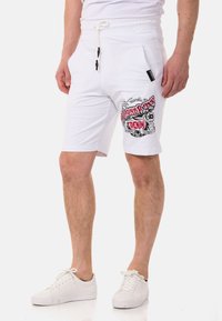 Weiße Baumwollshorts mit einem Kordelzugbund, versehen mit einem grafischen Druck in Rot und Schwarz auf dem linken Oberschenkel sowie zwei Seitentaschen.