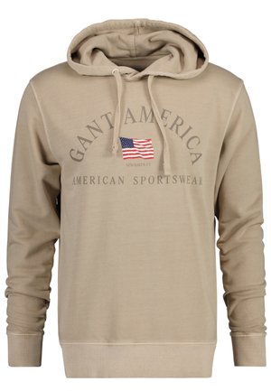 Sweat à capuche beige avec cordons, arborant un petit drapeau américain et les inscriptions « GANT AMERICA » et « AMERICAN SPORTSWEAR » sur le devant.