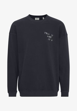 Tamsiai mėlynas džemperis, pagamintas iš medvilnės ir sintetinių pluoštų, su apvalia iškirpte ir ilgomis rankovėmis. Krūtinėje balta spalva atspausdintas tekstas "TELL IT LIKE IT IS".