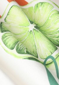 Katoen stof met een close-up print van gesneden limoen in verschillende tinten groen, tegen een witte achtergrond met subtiele textuurdetails.