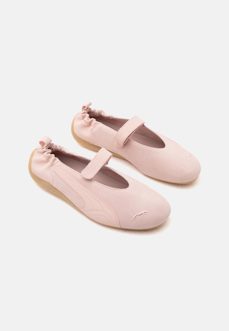 Paire de ballerines roses douces avec dos élastique, bride Velcro sur le dessus et semelles beige clair sur fond blanc.