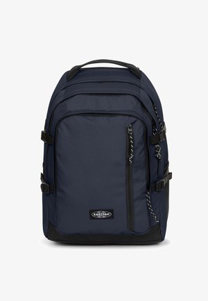 Granatowy plecak o teksturowanej powierzchni, z wieloma zamkami, regulowanymi paskami oraz czarną podstawą. Na froncie znajduje się logo marki.