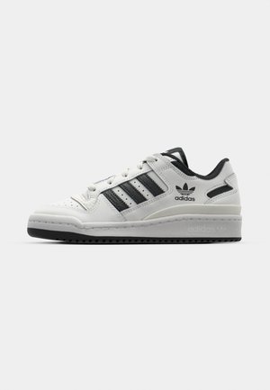 White leather sneakers with black accents, featuring three black stripes, a padded collar, and a textured rubber outsole.